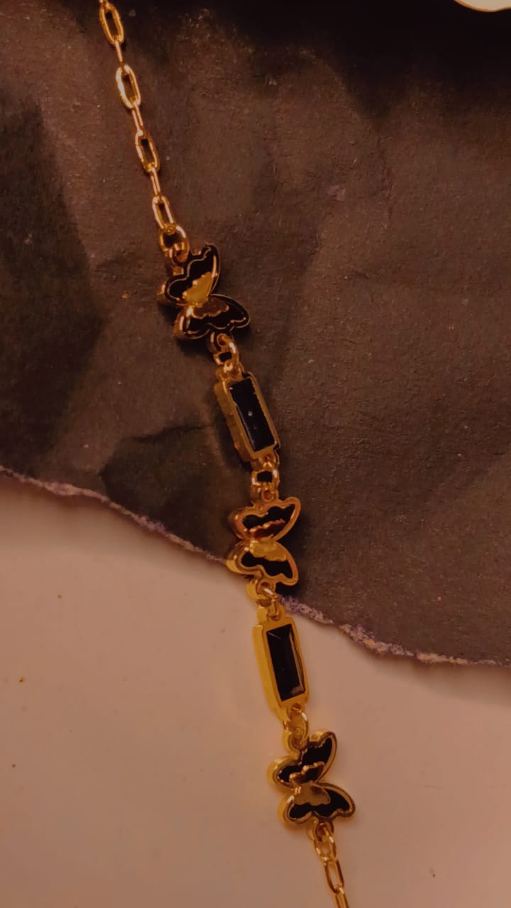 Gold bracelet with black butterfly charms and rectangular stones